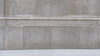 Femme marchant avec un sac à main noir le long d’un mur urbain minimaliste.